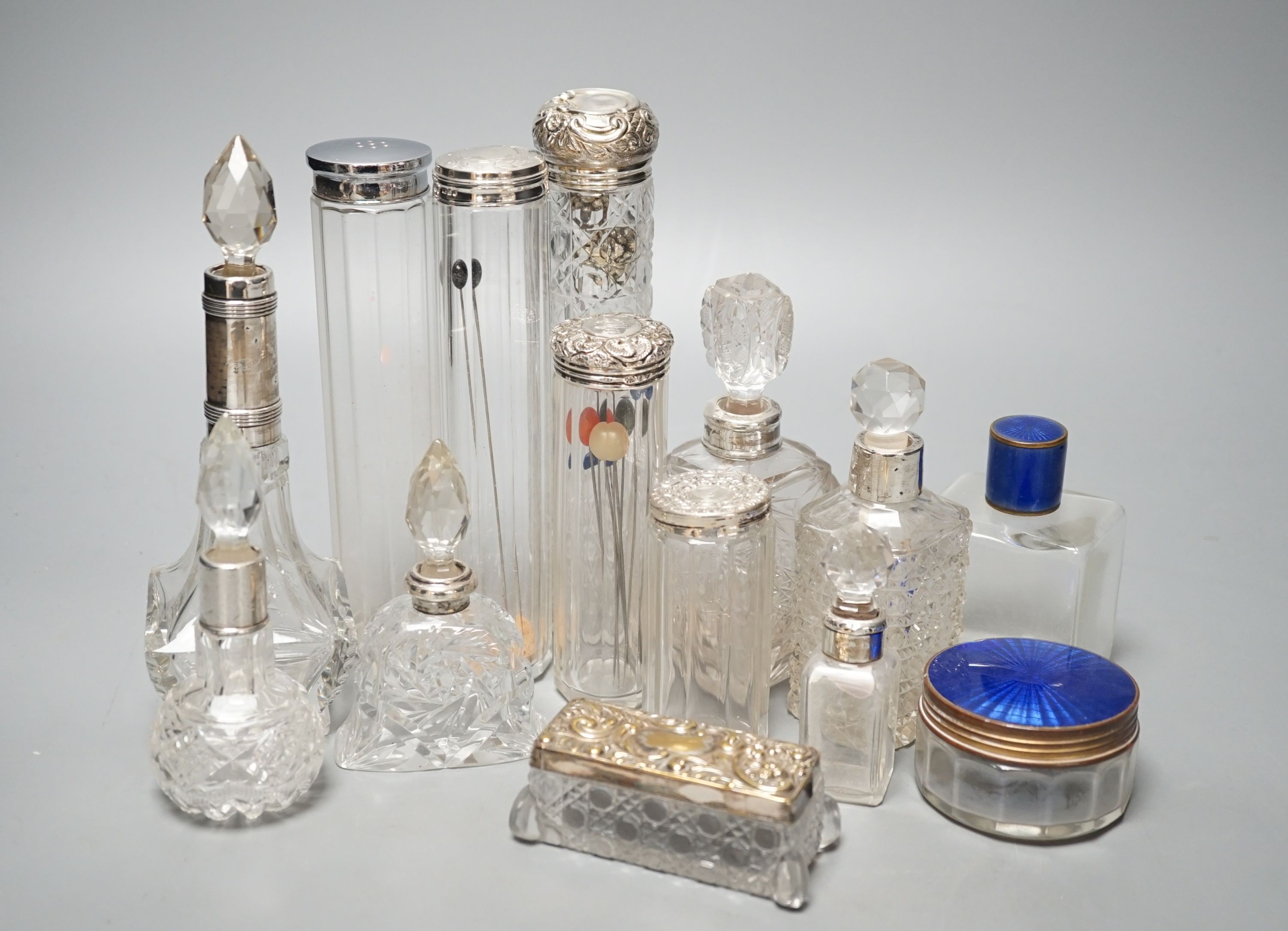 A collection of assorted mainly silver-capped scent bottles and toilet jars, etc. including two gilt metal and enamel.